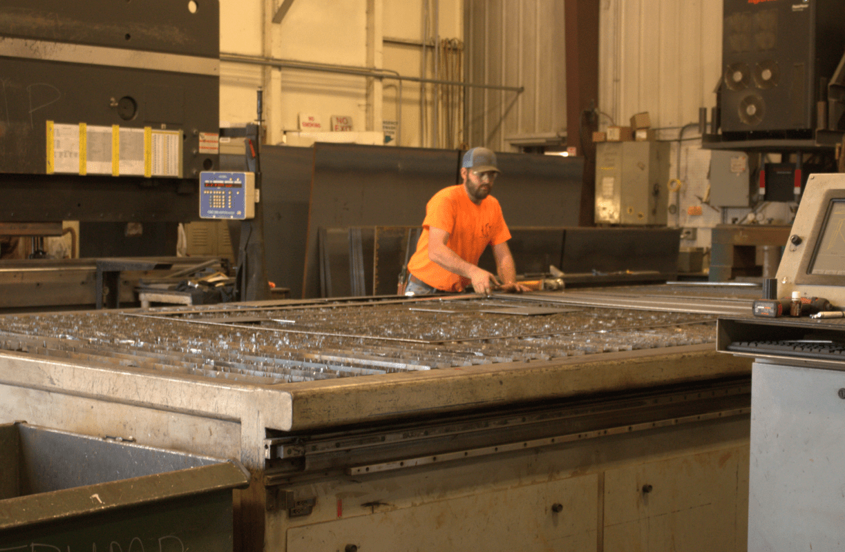 An inside view of the Seal Rite factory in Auxvasse, Missouri, showing workers at their stations and various machinery used in the production of asphalt and seal coating equipment.